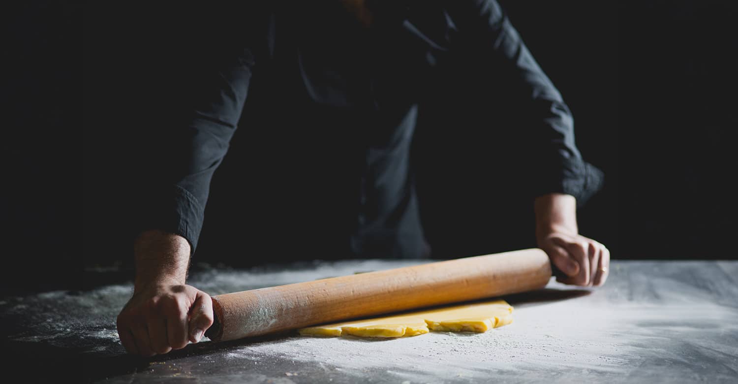 image of a man rolling out some pastry